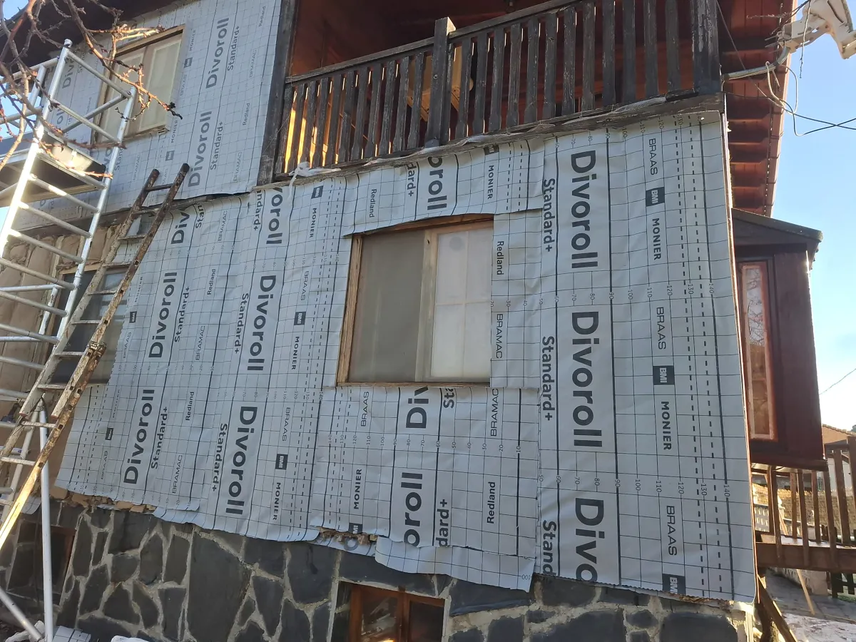 Casa de madera con membrana impermeable durante el revestimiento
